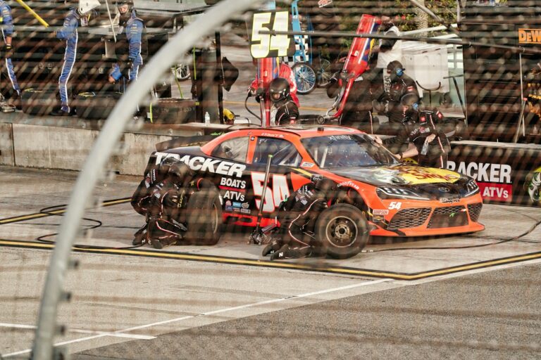 A focused pit crew services a Nascar racing car during an event in Miami.